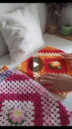 two crocheted bedspreads on a bed with white pillows and one has a pink flower