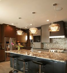 a kitchen with marble counter tops and two lights hanging from the ceiling over the island