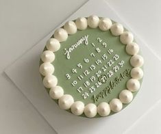 a green and white birthday cake on top of a card with the date printed on it