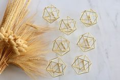 several gold geometric pieces next to some wheat stalks