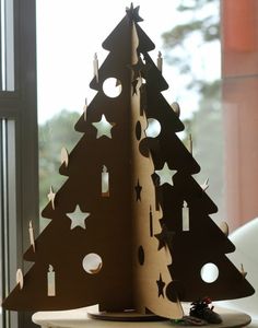 a wooden christmas tree sitting on top of a table next to a window