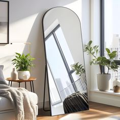 a large mirror sitting in the corner of a room next to a couch and potted plant