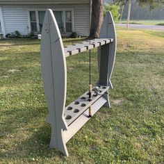 a surfboard shaped shelf sitting on top of a grass covered field next to a house