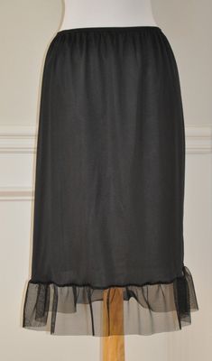 "An exquisite accessory for your wardrobe, this underskirt slip worn with your skirt or dress will make you feel very special ! It is made of black nylon with elastic waistband and black tulle ruffle trim 7\" long. Standard length is 25\" This accessory makes a perfect gift! Hand wash in cold water. Available in sizes: XS-0-2, Waist: 24 1/2\", Hip: 35\" S-4-6, Waist: 25 1/2\"-26 1/2\", Hip: 36-37\" M-8-10, Waist: 27 1/2-28 1/2\", Hip: 38-39\" L-12-14, Waist: 30-31 1/2\", Hip: 40 1/2-42\" XL-16-1 Elegant Stretch Tiered Skirt, Elegant Formal Skirt With Lace Trim, Elegant Maxi Skirt With Lace Trim, Elegant Tiered Skirt Party Petticoat, Elegant Tiered Skirt Petticoat For Party, Elegant Tiered Party Petticoat, Elegant Tiered Petticoat For Party, Elegant Black Petticoat For Party, Elegant Ruffled Skirt Petticoat