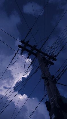 telephone poles and wires against a cloudy blue sky