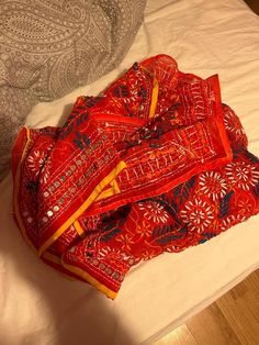 an orange and red scarf laying on top of a bed