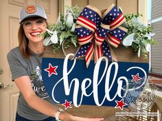 a woman holding up a sign with the word hello painted on it and an american flag bow