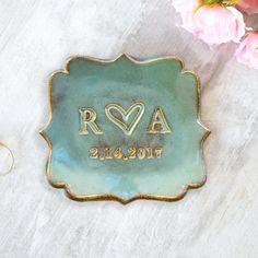 a personalized ceramic dish with the initials and date engraved on it next to pink flowers