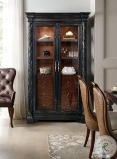 a room with a chair, desk and china cabinet in it's center area