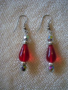 "Beautiful handmade drop earrings measure 2 1/8\" long. The earrings are in a silver tone setting and feature a red center drop bead with silver tone and iridescent beads on top and bottom. These earrings have a lot of sparkle and would dress up any outfit." Red Beaded Drop Crystal Earrings, Red Beaded Crystal Drop Earrings, Nickel Free Red Drop Earrings, Red Beaded Teardrop Dangle Earrings, Red Teardrop Earrings With Dangling Beads, Red Nickel-free Drop Crystal Earrings, Red Beaded Drop Earrings, Pierced, Red Nickel-free Teardrop Dangle Earrings, Red Beaded Dangle Earrings