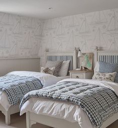 two twin beds in a bedroom with blue and white wallpaper