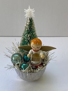 a tinker angel figurine sitting on top of a basket filled with ornaments