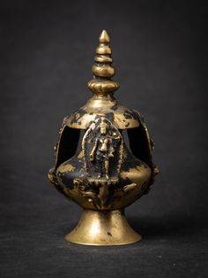 an ornate gold vase with a figure on it's side and a black background