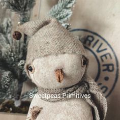 a stuffed snowman is sitting next to some pine cones and evergreen needles, with the word wool written on it