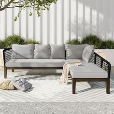 a couch sitting on top of a cement floor next to a tree and potted plants