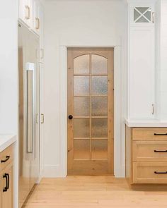 an empty kitchen with white walls and wooden cabinets, along with a clear glass door