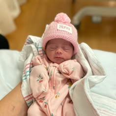 a newborn baby wearing a pink hat and laying on top of a person's arm