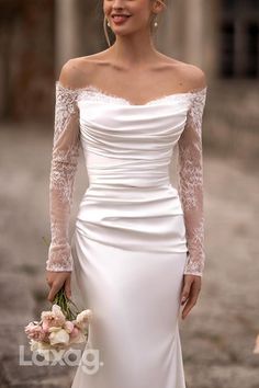 a woman in a white wedding dress holding a bouquet and posing for the camera with her hands on her hips