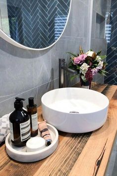 a bathroom sink sitting on top of a wooden counter next to a vase with flowers