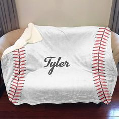 a baseball blanket with the word tyler on it sitting in front of a chair and window