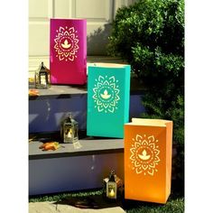 three brightly colored boxes sitting on the steps in front of a house with candles and lanterns