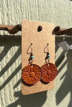 a pair of wooden earrings hanging from a hook on a piece of cardboard with a string attached to it