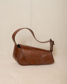 Trivia bag by Kiko Kostadinov in mahogany brown. The signature handbag silhouette from Kiko Kostadinov, presented in deep mahogany calf leather with intricate brogue detailing around the edges. Foldover flap with magnetic closure main compartment. Born in Bulgaria and based in London, Kiko Kostadinov launched his eponymous womenswear line in 2018, delving into an avant-garde aesthetic with innovative fabrics and architectural silhouettes. With Australians Laura and Deanna Fanning at the creative Designer Brown Flap Bag With Top Handle, Designer Brown Top Handle Flap Bag, Brown Textured Leather Flap Bag For Evening, Brown Leather Evening Shoulder Bag, Luxury Brown Saddle Satchel, Brown Leather-lined Shoulder Bag For Evening, Brown Calf Leather Shoulder Bag With Removable Pouch, Brown Leather Lined Shoulder Bag For Evening, Formal Brown Textured Leather Flap Bag