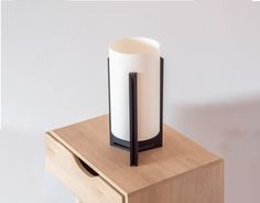 a white and black vase sitting on top of a wooden table next to a drawer