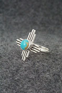 This turquoise and sterling silver ring featuring a traditional Zia Symbol was made by Santo Domingo silversmith Raymond Coriz. The inside is signed and stamped sterling.Size: 8Length: 7/8"Width: 7/8"Free shipping on all orders! We ship with USPS and always include tracking. All orders ship within a day of payment.Returns are accepted up to 30 days after you receive your order. Just send us a message. Our shop offers cash back or store credit. The item must be returned in new condition. Southwestern Polished Turquoise Ring Collectible, Artisan Sterling Silver Turquoise Ring With Polished Finish, Artisan Turquoise Ring In Sterling Silver With Polished Finish, Southwestern Polished Turquoise Ring, Southwestern Style Polished Turquoise Ring, Nickel-free Southwestern Sterling Silver Rings, Southwestern Style Nickel-free Sterling Silver Rings, Southwestern Silver Turquoise Open Ring, Southwestern Style Silver Turquoise Open Ring