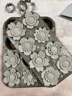 there are many cookies in the shape of flowers on this tray, and one is shaped like a heart