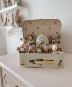 a suitcase filled with stuffed animals sitting on top of a white dresser