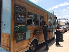 two men standing in front of a food truck with menus on the side of it