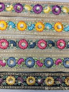 multicolored flowers are arranged on the side of a piece of cloth with beading