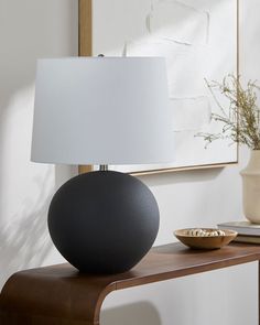 a table with a lamp on top of it next to a bowl and vases