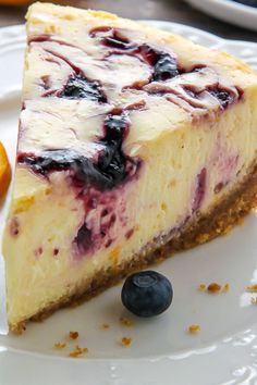 a slice of cheesecake with blueberries on a plate next to an orange wedge