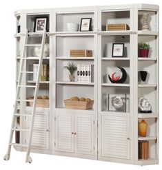 a white bookcase filled with lots of books and shelves next to a stair case