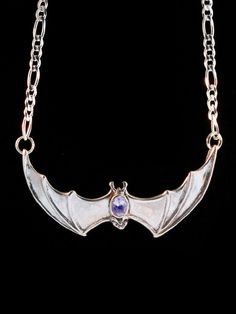 "This solid sterling silver Bat pendant would love to hang around your neck. It's wing span is 2 1/4\" across. A 16\" figaro chain is attached to both wing tips and is included in the price of this piece making the total length of the pendant just over 18\". A 5mm x 7mm gemstone is bezel set in the back of the bat. Take flight with one tonight. Please select your desired gemstone in the dropdown options menu. You may choose between a Blue Topaz, Citrine, Amethyst, Peridot, Black Onyx or Mozambiq Gothic Winged Jewelry For Gifts, Gothic Winged Jewelry Gift, Silver Winged Engraved Jewelry, Gothic Sterling Silver Jewelry With Polished Finish, Gothic Sterling Silver Jewelry, Engraved Halloween Pendant Jewelry, Engraved Winged Sterling Silver Jewelry, Gothic Gemstone Jewelry For Collectors, Nickel-free Silver Winged Jewelry