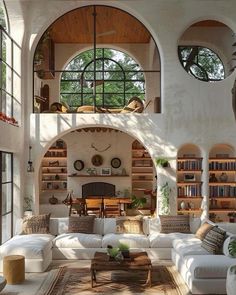 a living room filled with white furniture and lots of books on the shelves in front of an arched window