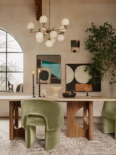 a dining room with green chairs and art on the wall