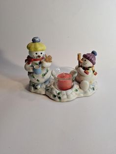 two snowmen sitting next to each other with a candle