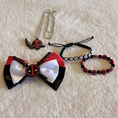 three pieces of jewelry are laid out on a white surface, including a red and black bow tie