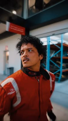 a man with curly hair wearing an orange jacket