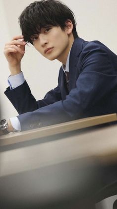 a young man sitting at a desk with his hand on his head and looking off to the side