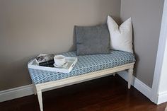 a blue bench with two pillows on it in a living room next to a wall