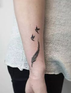 a woman with a tattoo on her arm that has birds flying in the sky above it