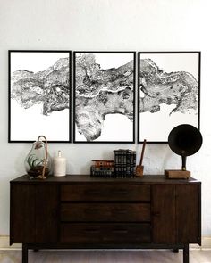 two black and white pictures hanging on the wall next to a wooden dresser with books