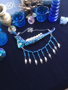 This is a Beautiful Painted, Blue and Purple Crystal Deer Jawbone Necklace! The Colors Here Are Just Fantastic! The Painted crystals Are a Light Blue Color And The Backdrop is Purple! A few rhinestones as well. Hanging from the bottom is a Bib of Glass beads! All 6 Teeth Are in perfect condition. The Whole Jaw Bone is 9 inches long. Also coated with polyurethane for the beautiful shine. The Chain is 20 inches long. All Items Ship Within 1-3 Days via USPS First Class Service. Shipping on This Bon Artistic Blue Necklaces For Festivals, Artistic Blue Necklace For Festivals, Artistic Blue Jewelry For Festivals, Handmade Blue Fantasy Jewelry, Hand Painted Blue Spiritual Necklace, Oddity Decor, Real Bone Jewelry, Animal Bone Jewelry, Wiccan Necklace