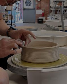 a woman is making a vase out of clay on a potter's wheel with her hands