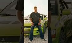 a man sitting on the hood of a green car