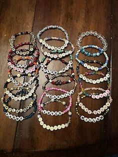 six bracelets with different colors and designs on the ends, sitting on a wooden table